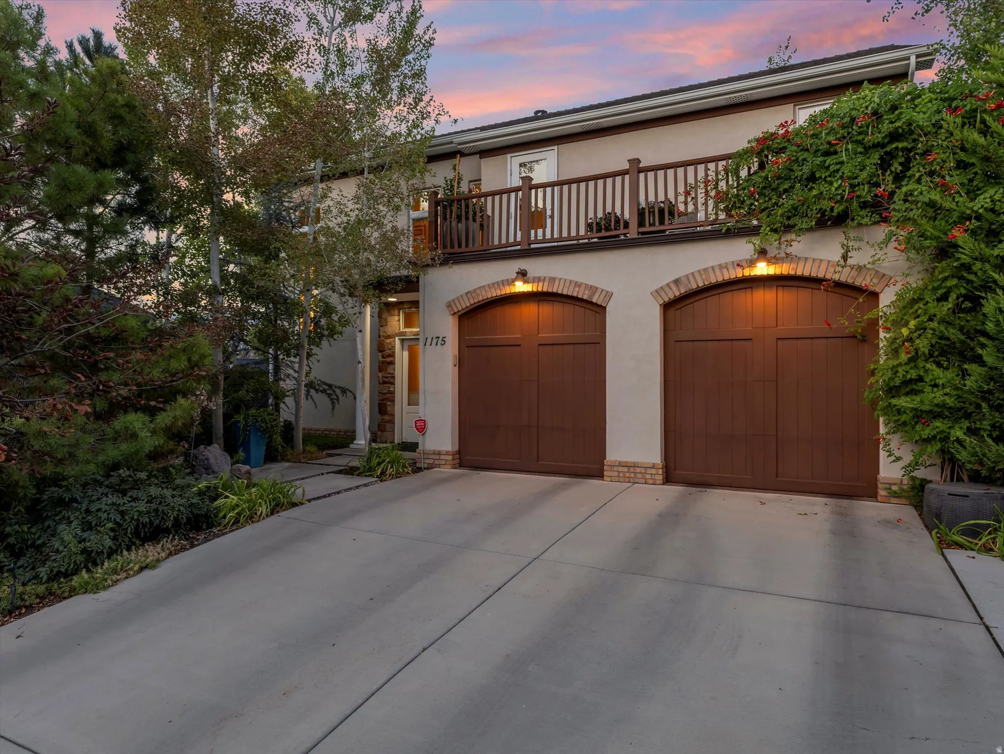 Mediterranean / spanish house with a balcony, stucco siding, concrete driveway, and an attached garage