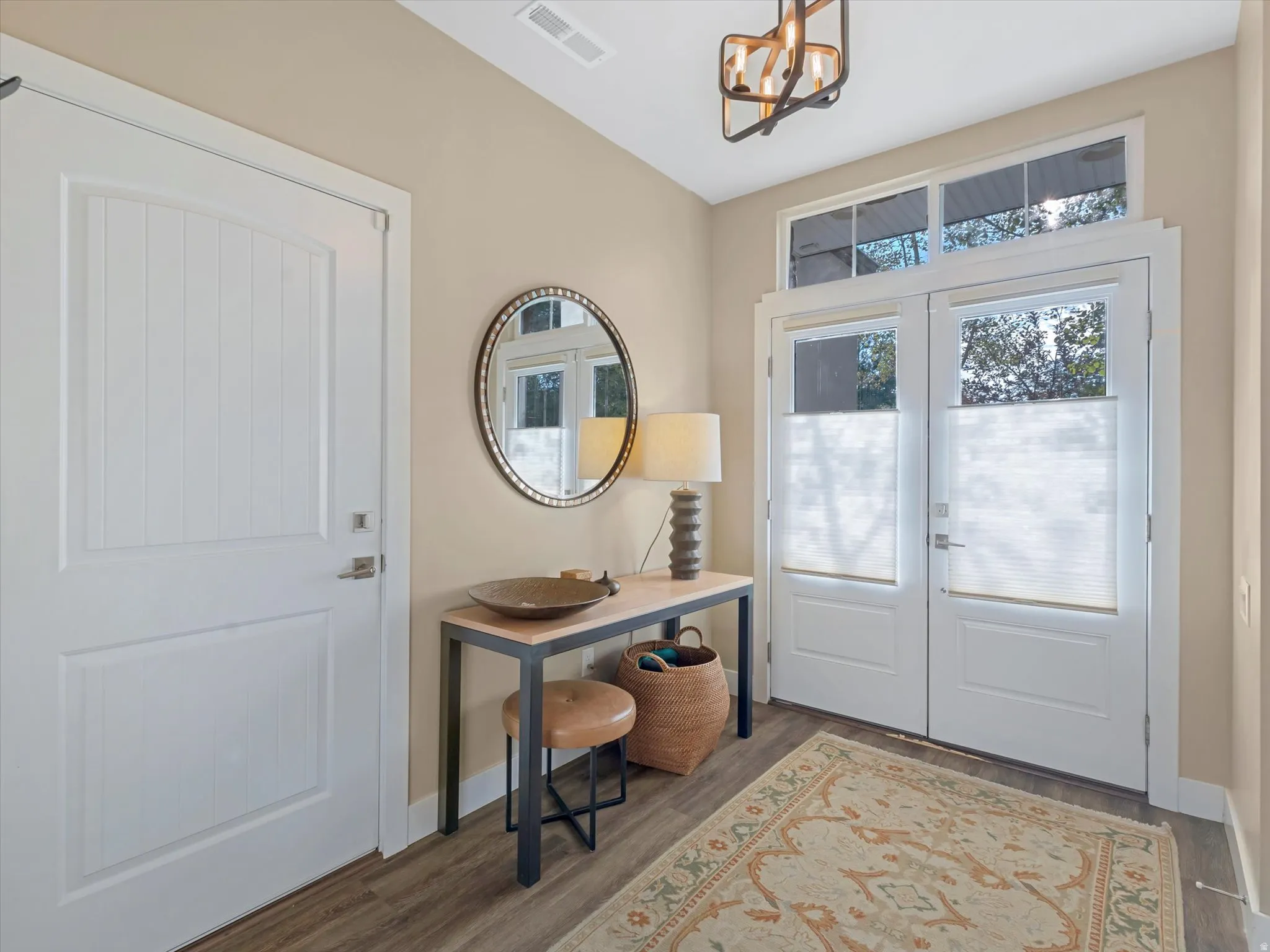 Foyer featuring wood finished floors, french doors, and a chandelier