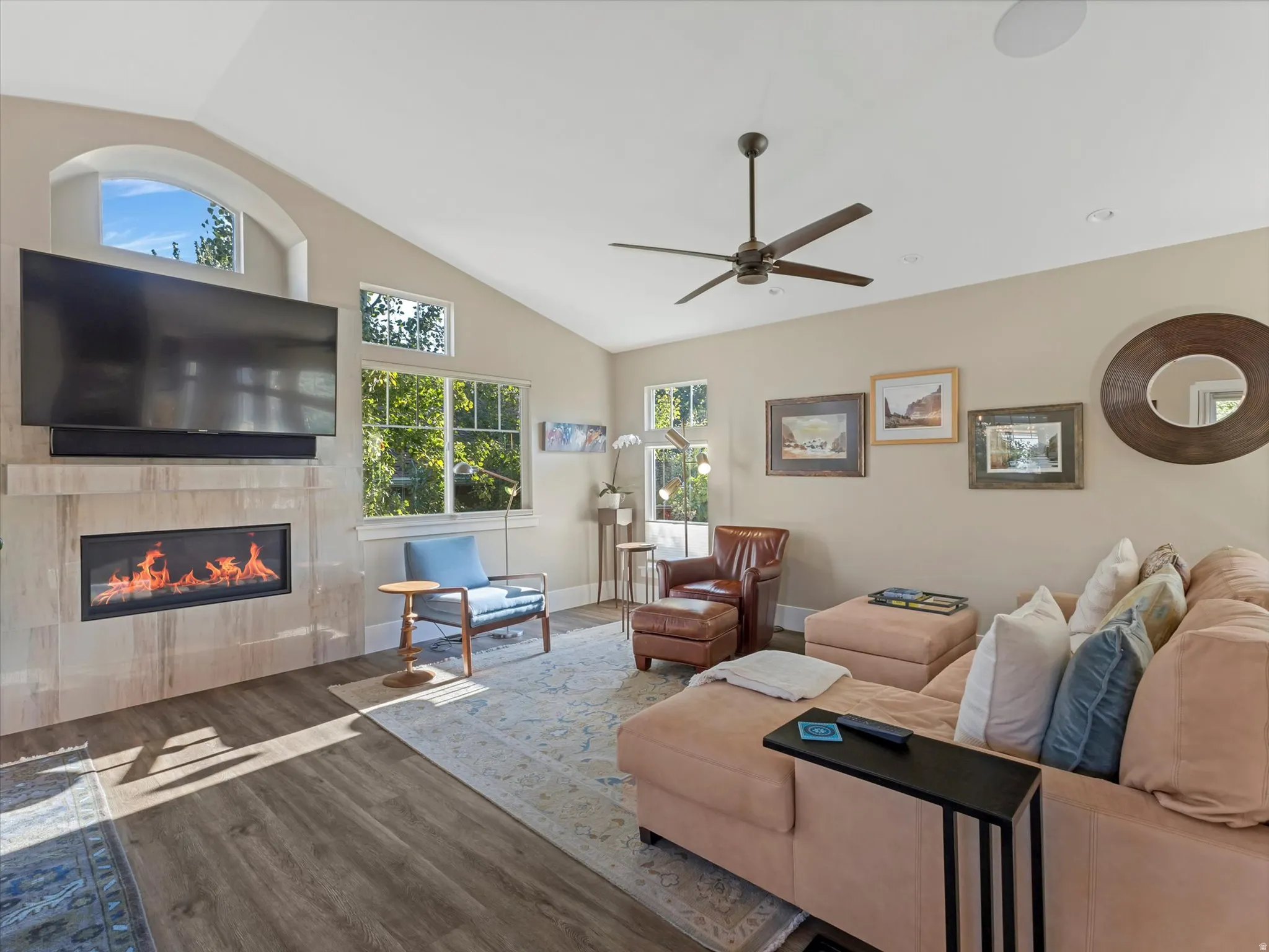 Living area with lofted ceiling, wood finished floors, a tiled fireplace, and a ceiling fan