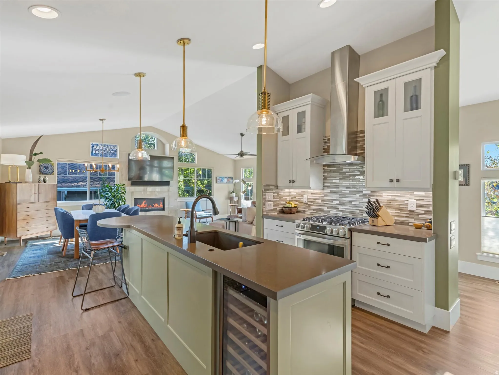 Kitchen with wall chimney range hood, open floor plan, wine cooler, gas range, and tasteful backsplash