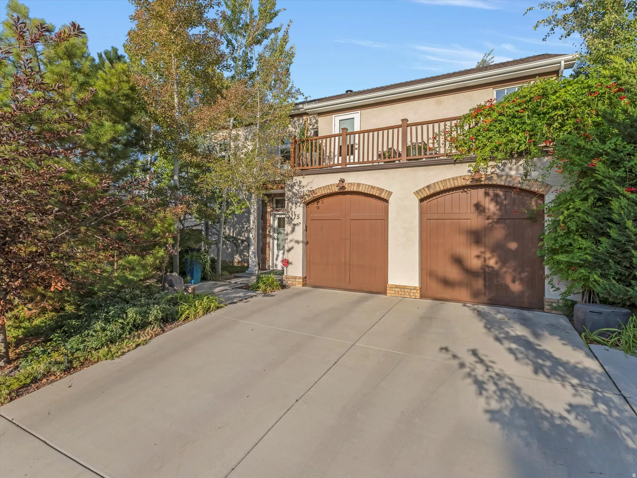 View of front facade featuring stucco siding, a balcony, concrete driveway, and a two-car garage