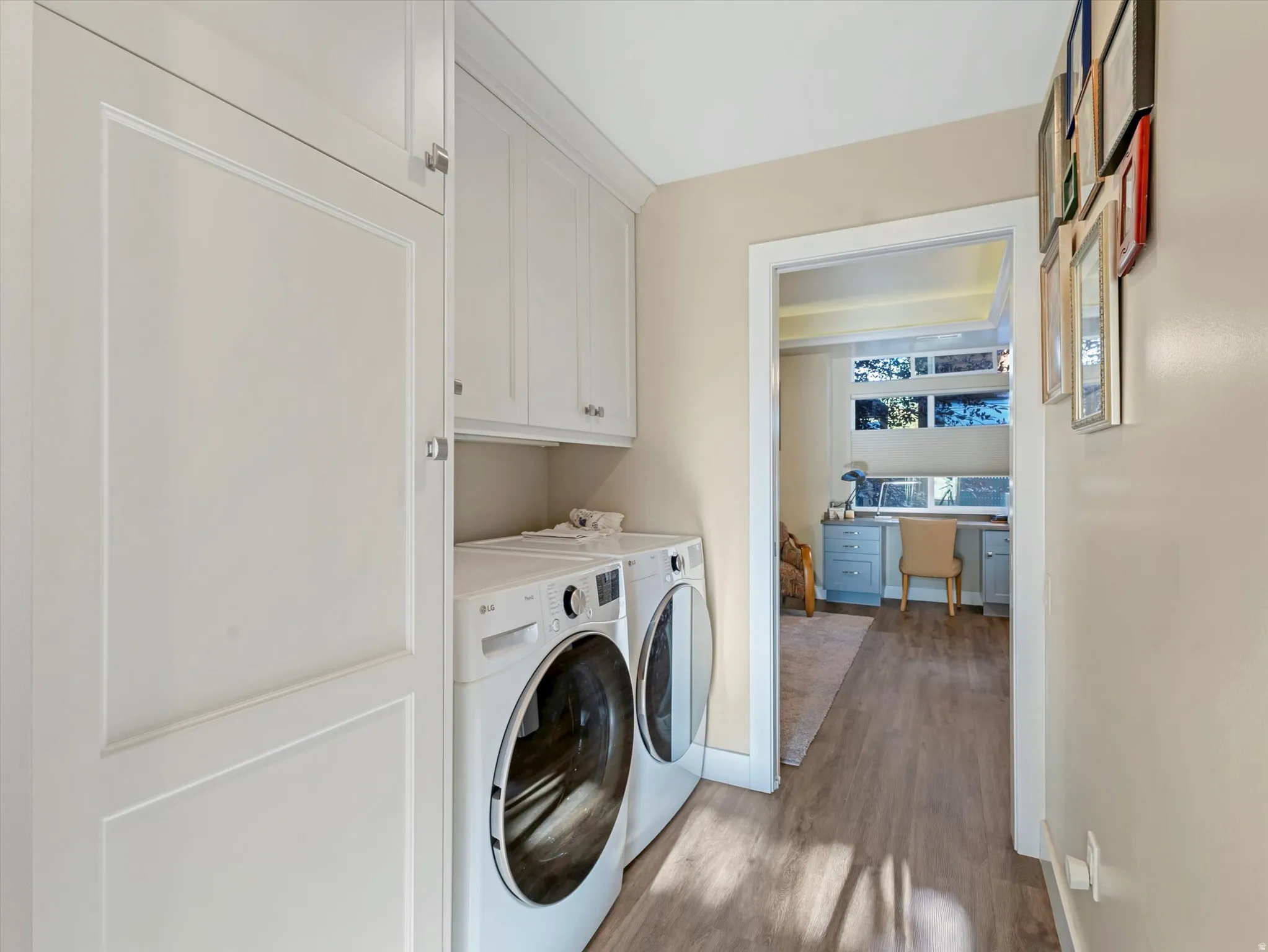Washroom featuring a desk, dark wood-style flooring, cabinet space, and washing machine and clothes dryer