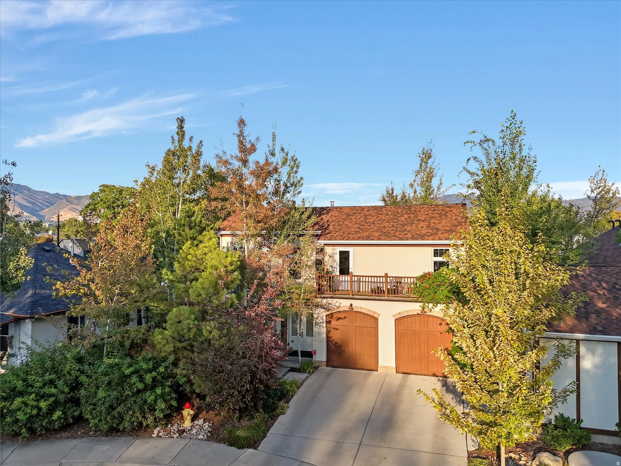View of front of house with stucco siding, driveway, a balcony, and an attached garage
