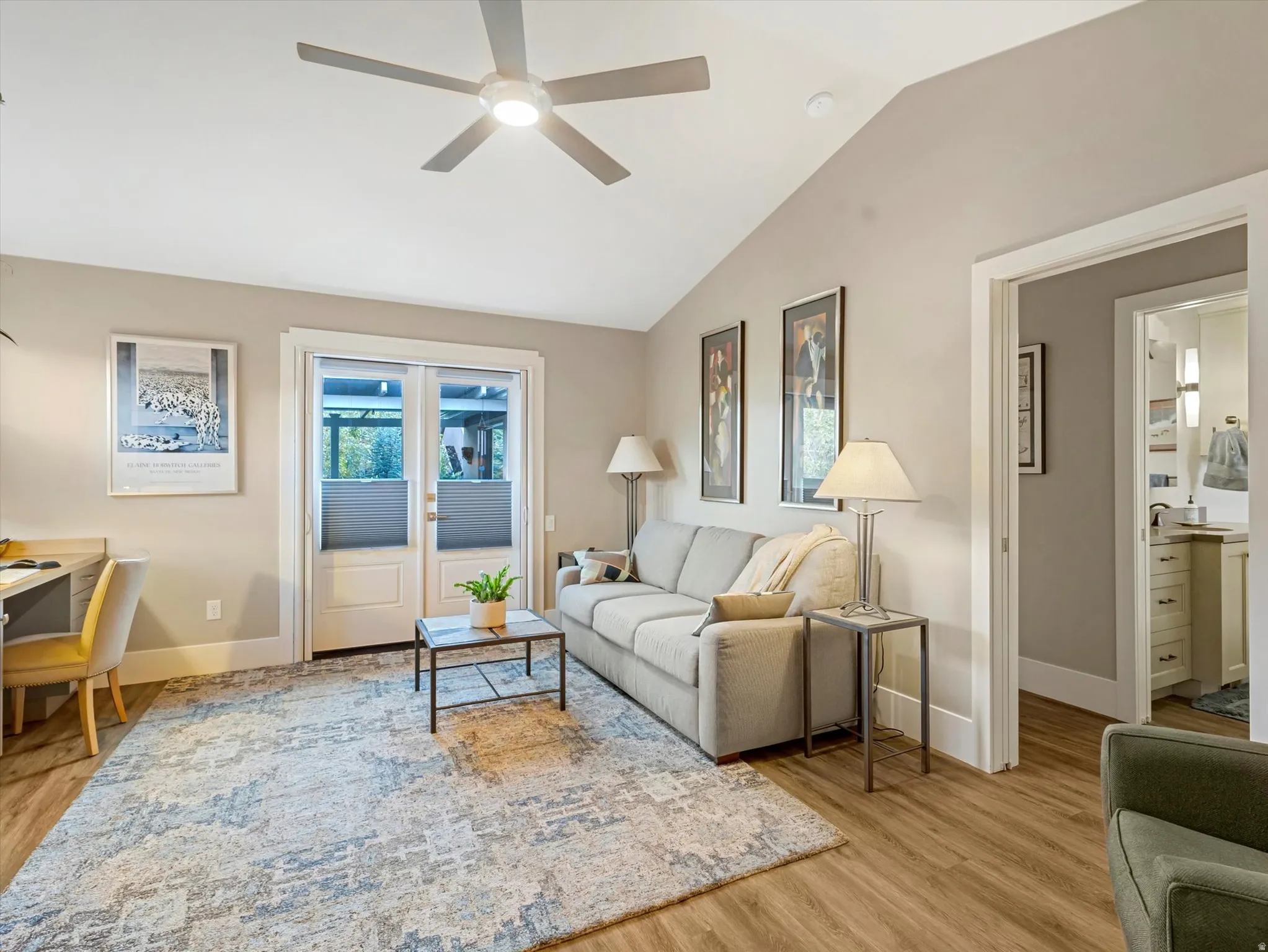 Living area with light wood-type flooring, vaulted ceiling, and ceiling fan