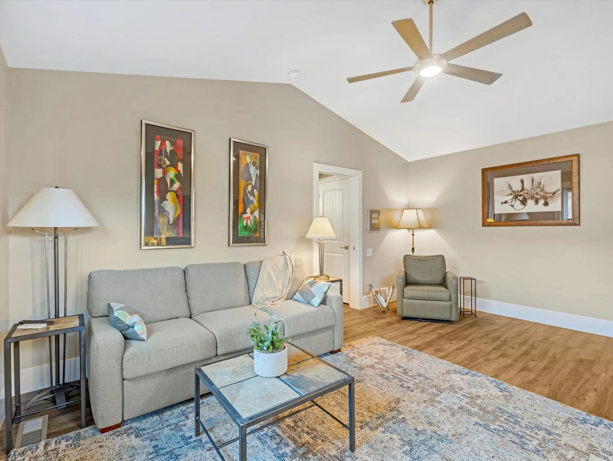 Living room featuring lofted ceiling, wood finished floors, and a ceiling fan