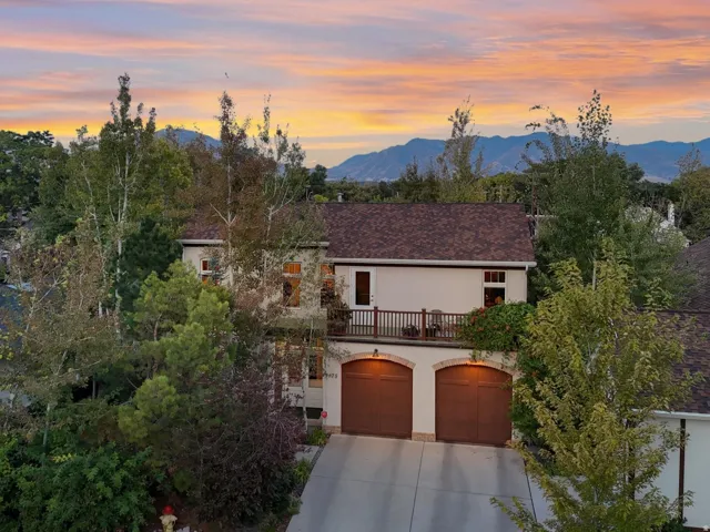View of front facade featuring driveway, a mountain view, stucco siding, a balcony, and a garage
