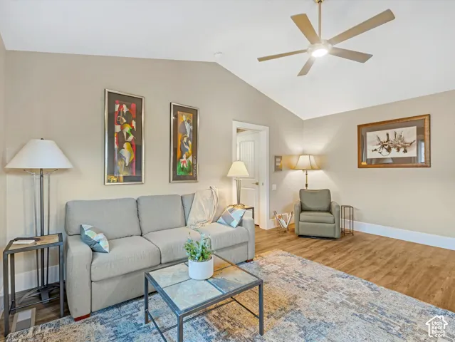 Living room featuring lofted ceiling, wood finished floors, and a ceiling fan