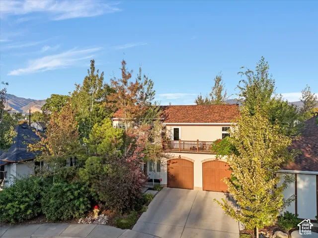 View of front of house with stucco siding, driveway, a balcony, and an attached garage