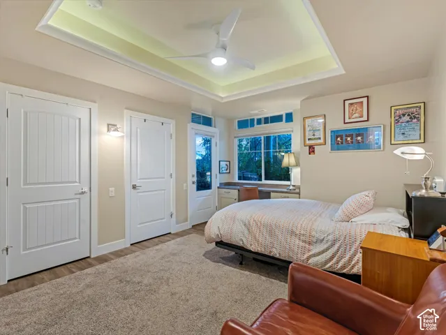 Bedroom with a raised ceiling, ceiling fan, and wood finished floors