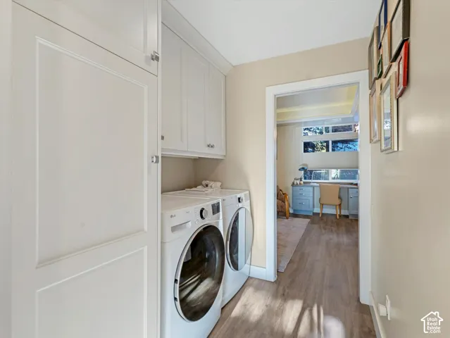 Washroom featuring a desk, dark wood-style flooring, cabinet space, and washing machine and clothes dryer