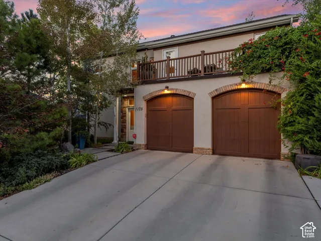 Mediterranean / spanish house with a balcony, stucco siding, concrete driveway, and an attached garage