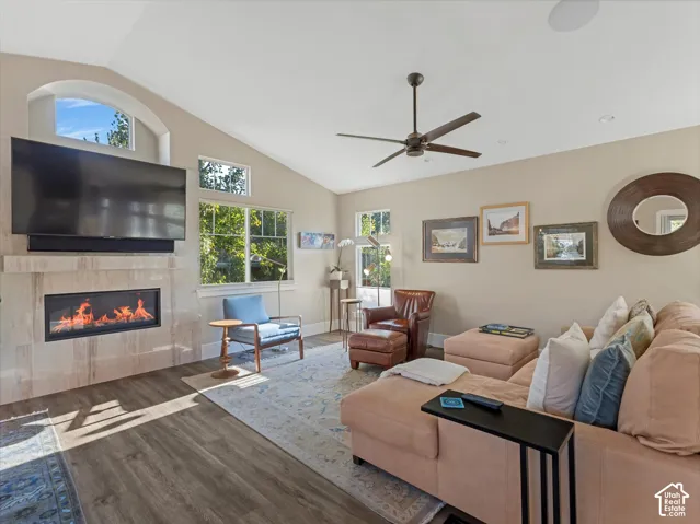 Living area with lofted ceiling, wood finished floors, a tiled fireplace, and a ceiling fan