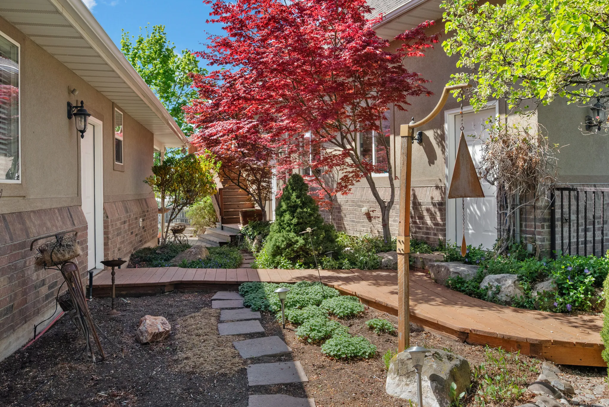 Landscaped exterior walkway featuring a vibrant red Japanese maple tree