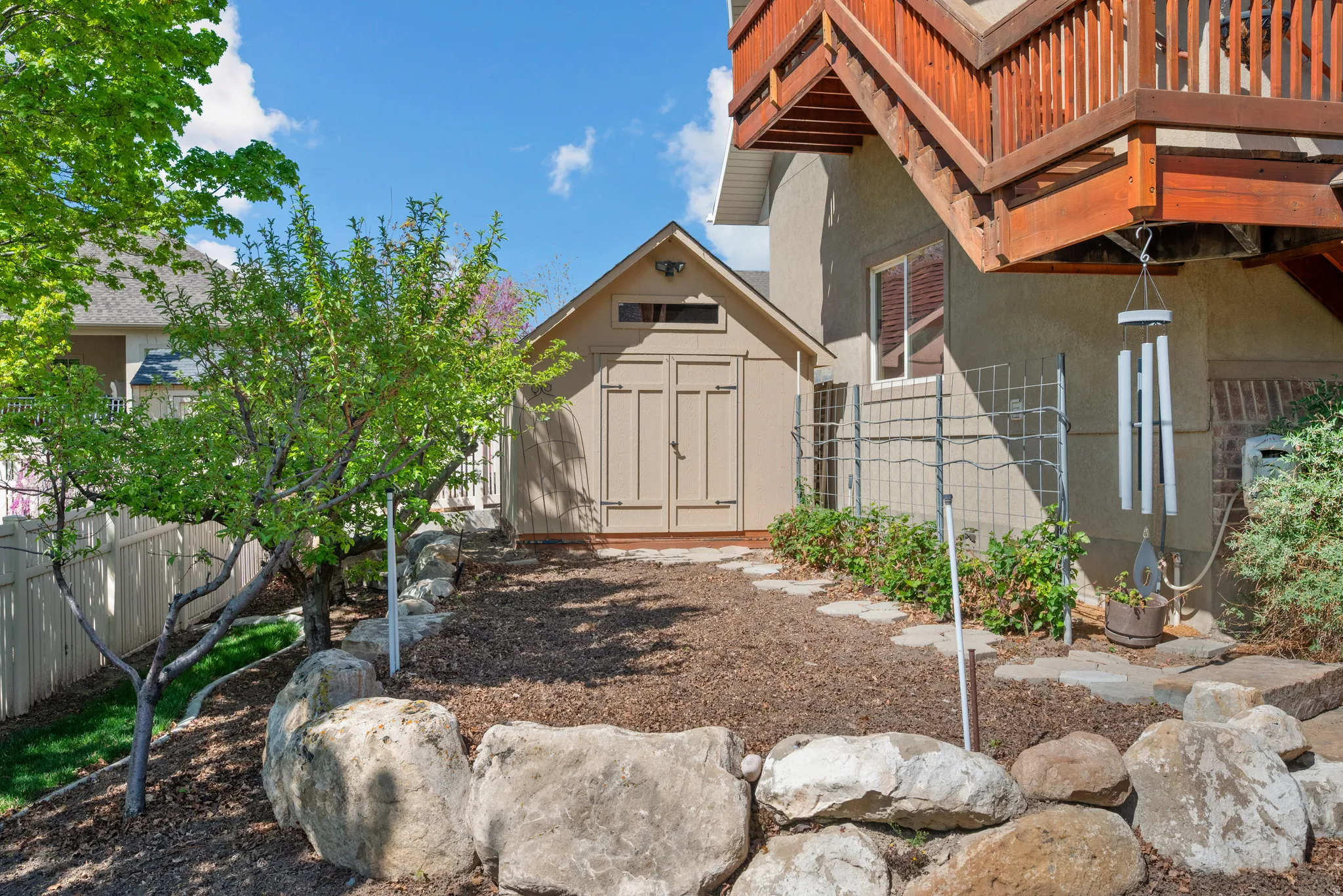 Private outdoor area with a wooden storage shed, rock retaining wall, mature trees