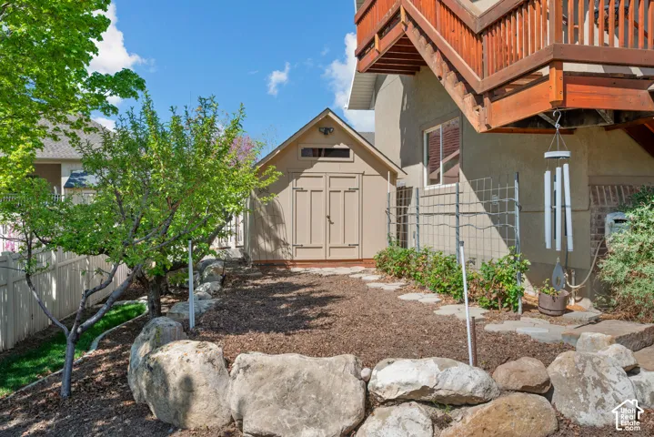 Private outdoor area with a wooden storage shed, rock retaining wall, mature trees
