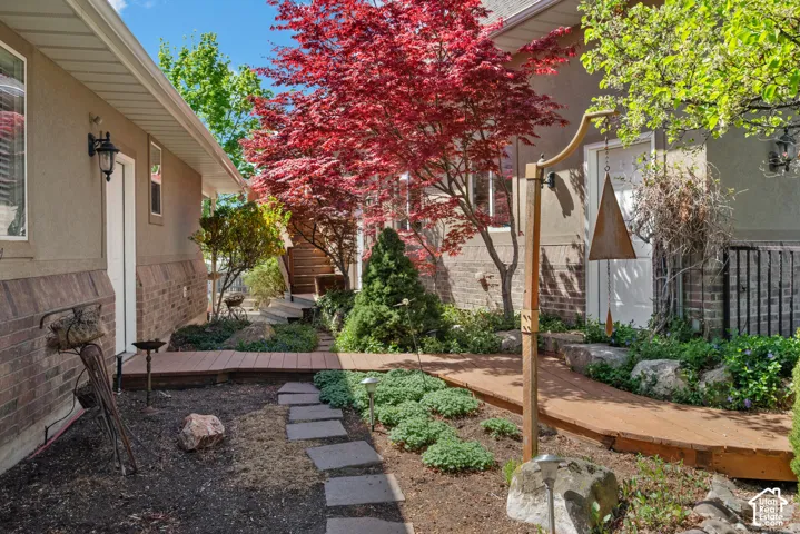 Landscaped exterior walkway featuring a vibrant red Japanese maple tree