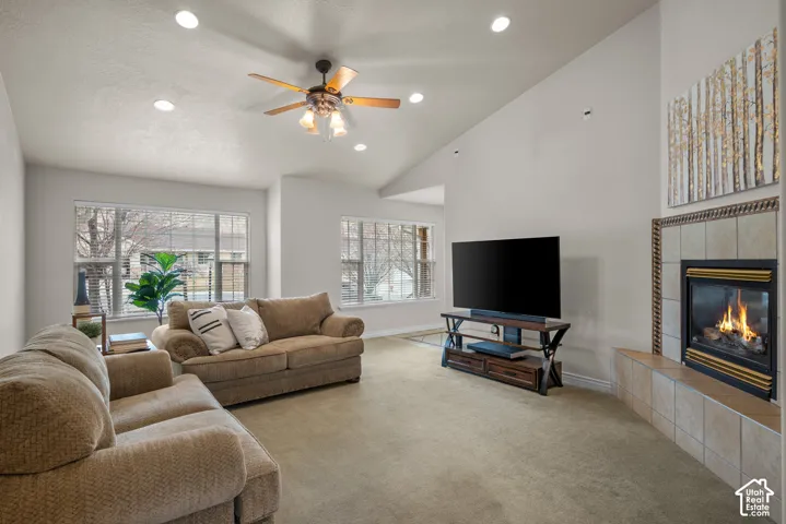 Living room featuring a gas fireplace with a tiled surround, vaulted ceilings, recessed lighting, and a ceiling fan
