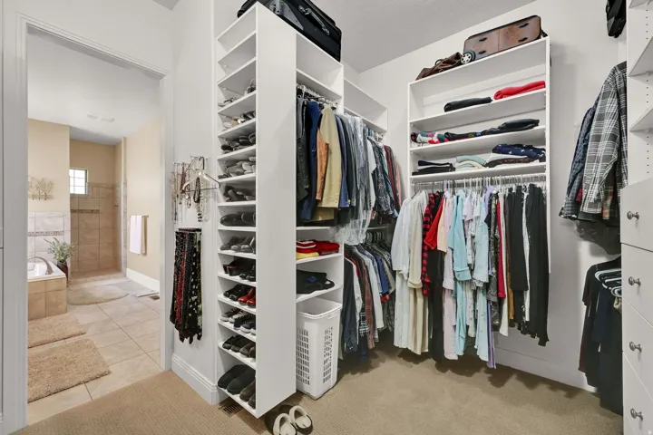 Expansive walk-in closet with extensive built-in shelving, multiple hanging rods, dedicated shoe storage, and this only shows half of it.