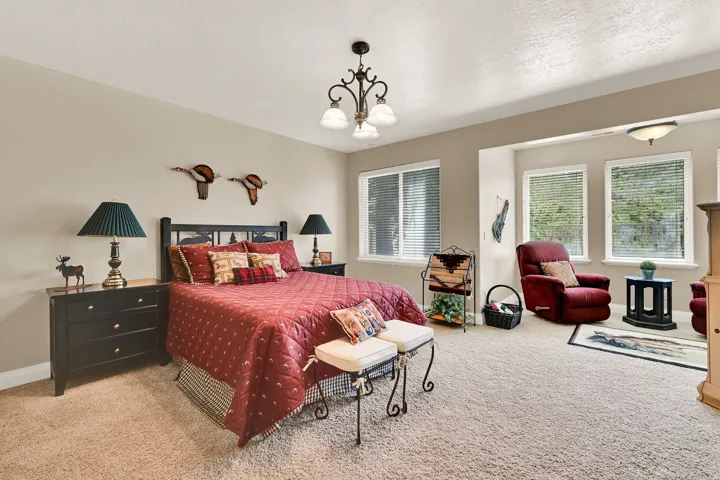 Carpeted room featuring multiple windows with blinds, a decorative chandelier, and recessed lighting