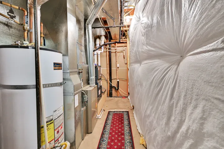 Utility area featuring a water heater, furnace system, and exposed ductwork