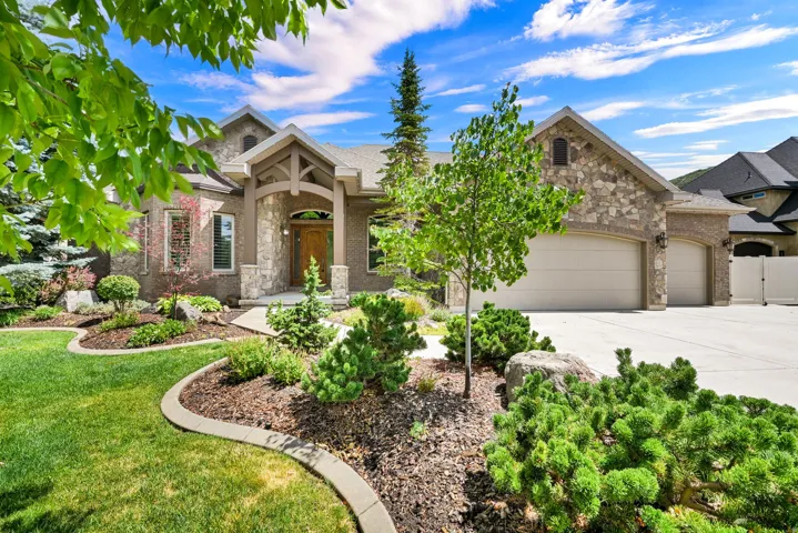 Stone and stucco exterior featuring a covered entry, arched front door, and a three-car garage.