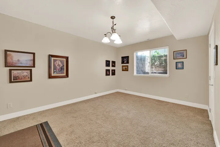 Carpeted interior room with neutral-toned walls, white baseboards, and a single window with horizontal blinds
