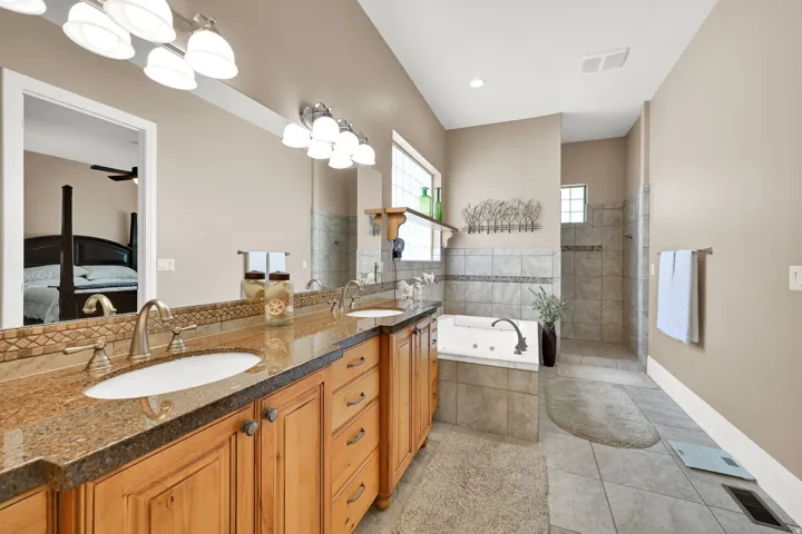 Primary bathroom featuring a double vanity, granite countertops and tons of lighting.