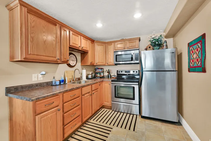 Kitchenette with a considerable amount of cabinet and counter space,  stainless steel appliances, and a tile flooring.