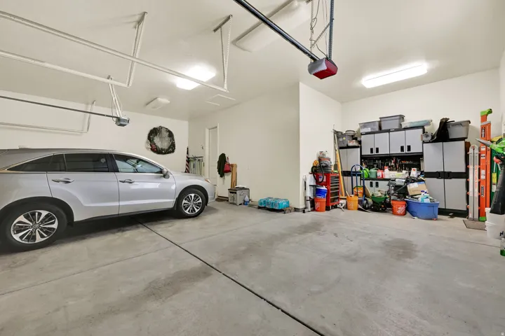 Spacious garage with light-colored concrete flooring, overhead lighting, and built-in storage cabinetry