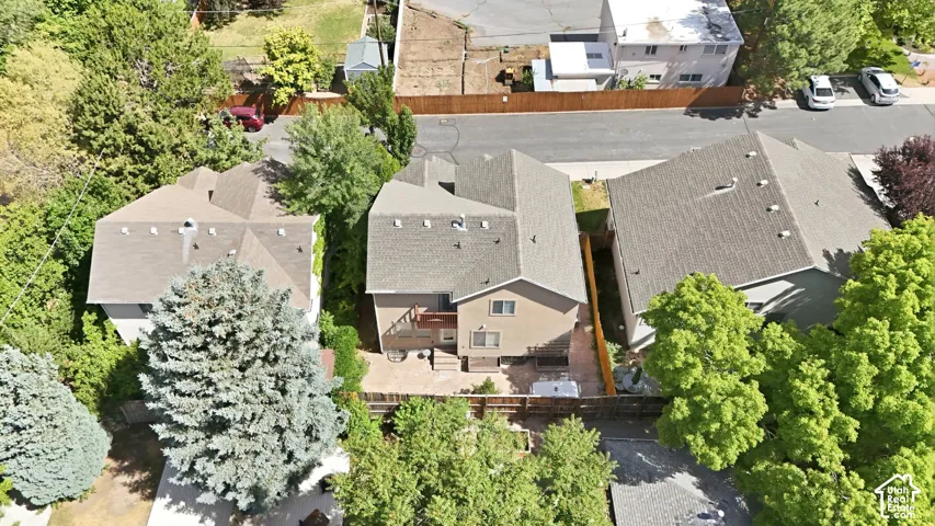 Residential property featuring a multi-level roofline, fenced backyard with mature trees, and a ground-level patio space