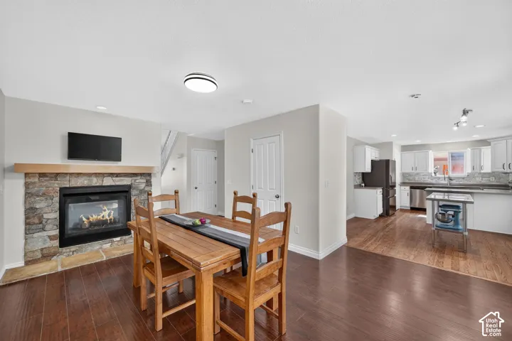 Living space featuring a stone-surround fireplace with a wood mantel, wood-finish flooring, and white walls