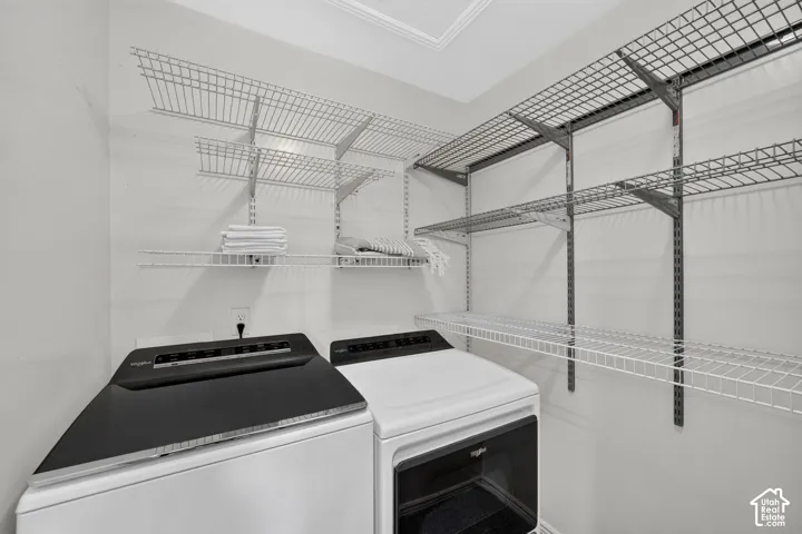 Utility room featuring white wire shelving, gray wire shelving, white walls, built-in shelving, and crown molding
