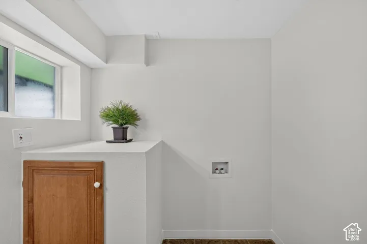 Laundry area featuring a window, light wood-finish cabinetry, and utility hookups