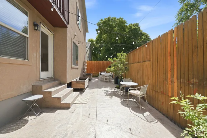 Expansive stamped concrete patio featuring privacy fencing, exterior lighting, and built-in planter boxes