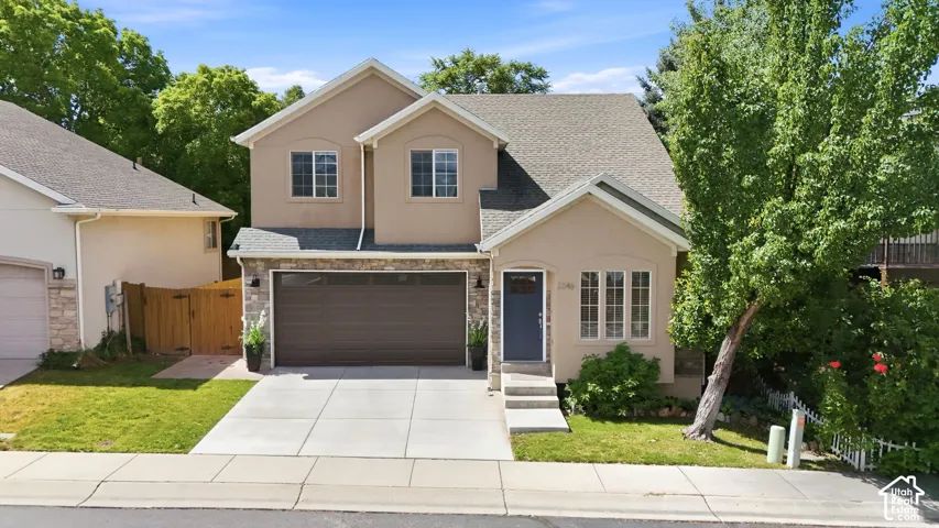 Two-story stucco residence featuring a stone-clad garage facade, an attached two-car garage, and a concrete driveway