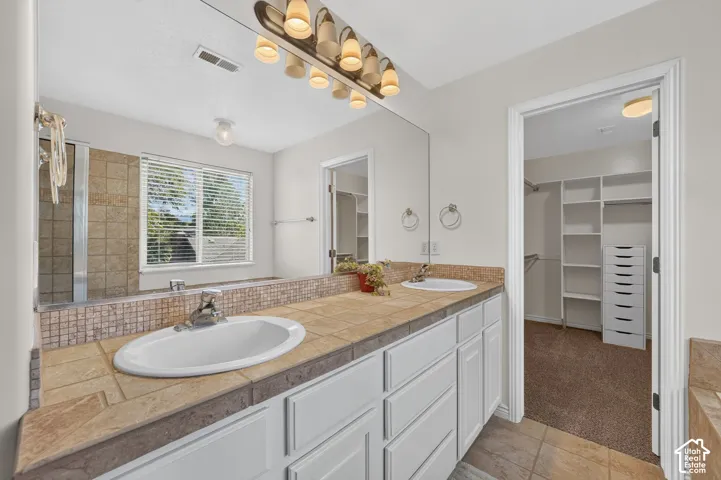 Dual vanity with integrated sinks, tiled countertop, and a full-width mirror