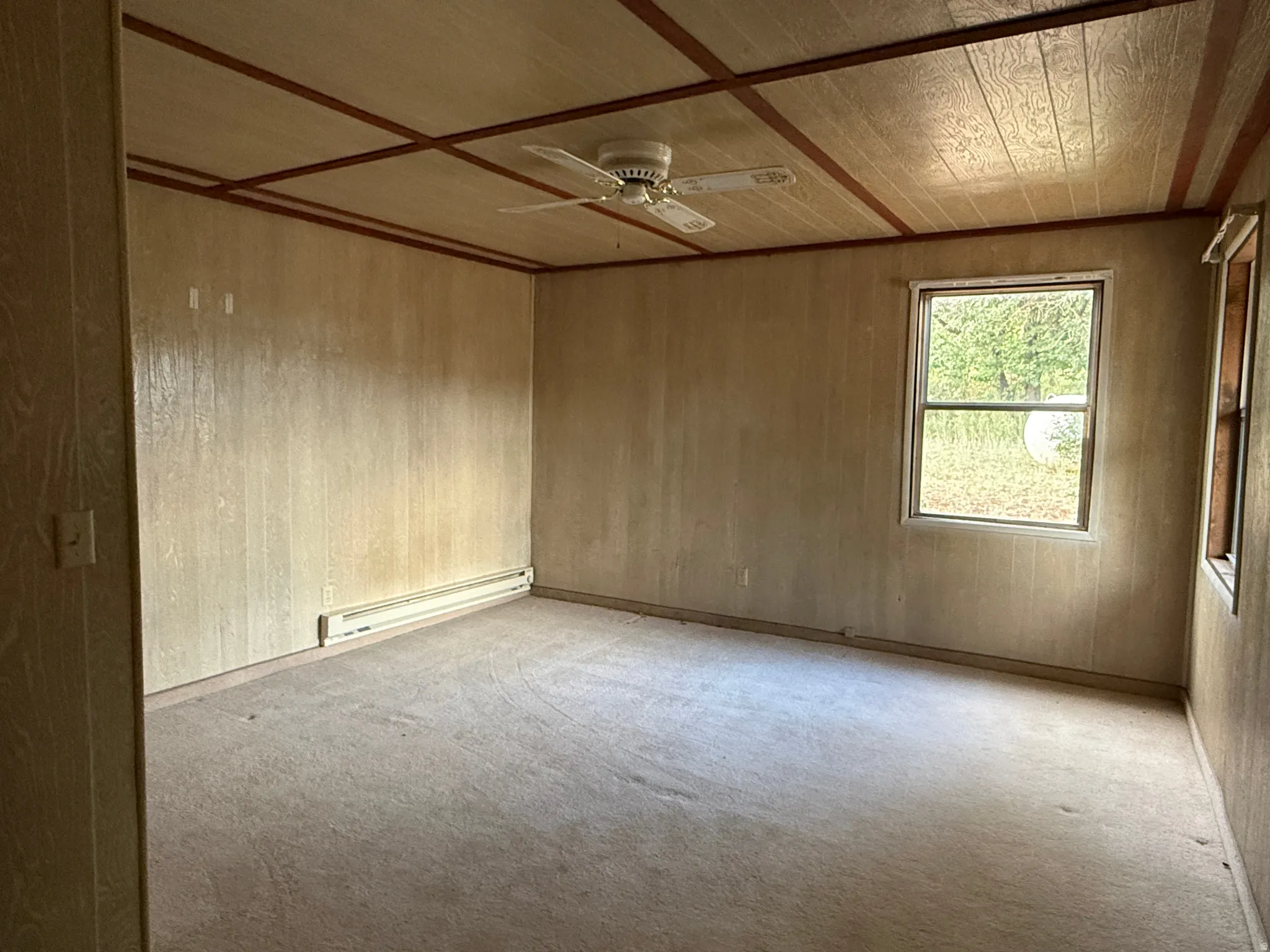Room with paneling walls, a window, and a ceiling fan