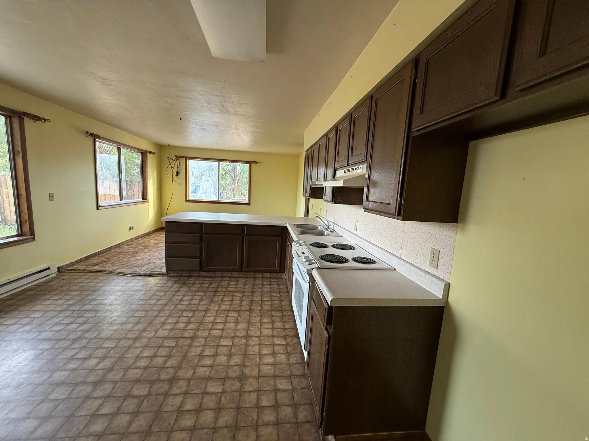 Open-concept kitchen and dining area featuring dark wood-finish cabinetry, white countertops, and white appliances