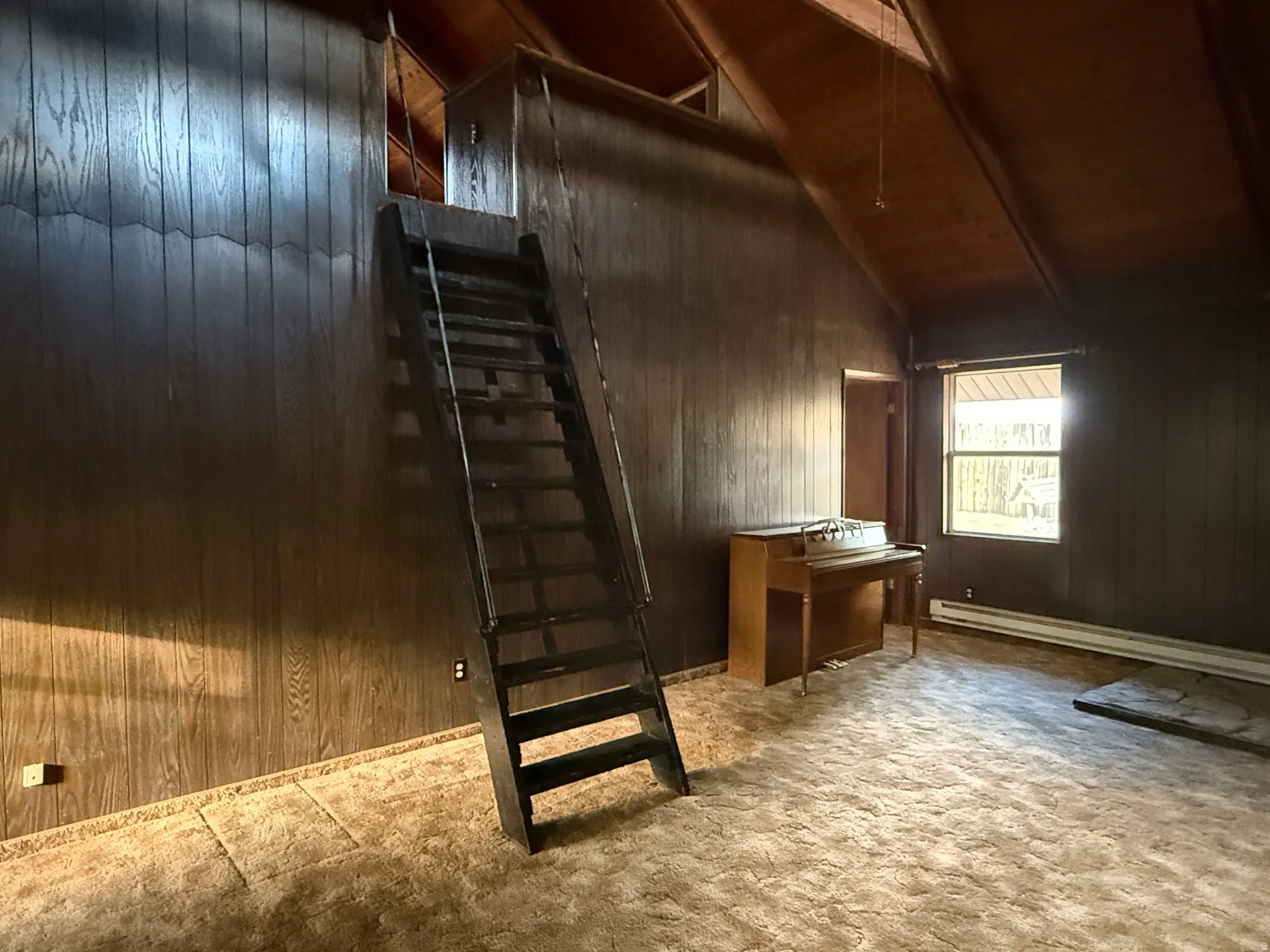 Vaulted wood-finish ceilings and walls with a fixed wooden ladder accessing an upper loft