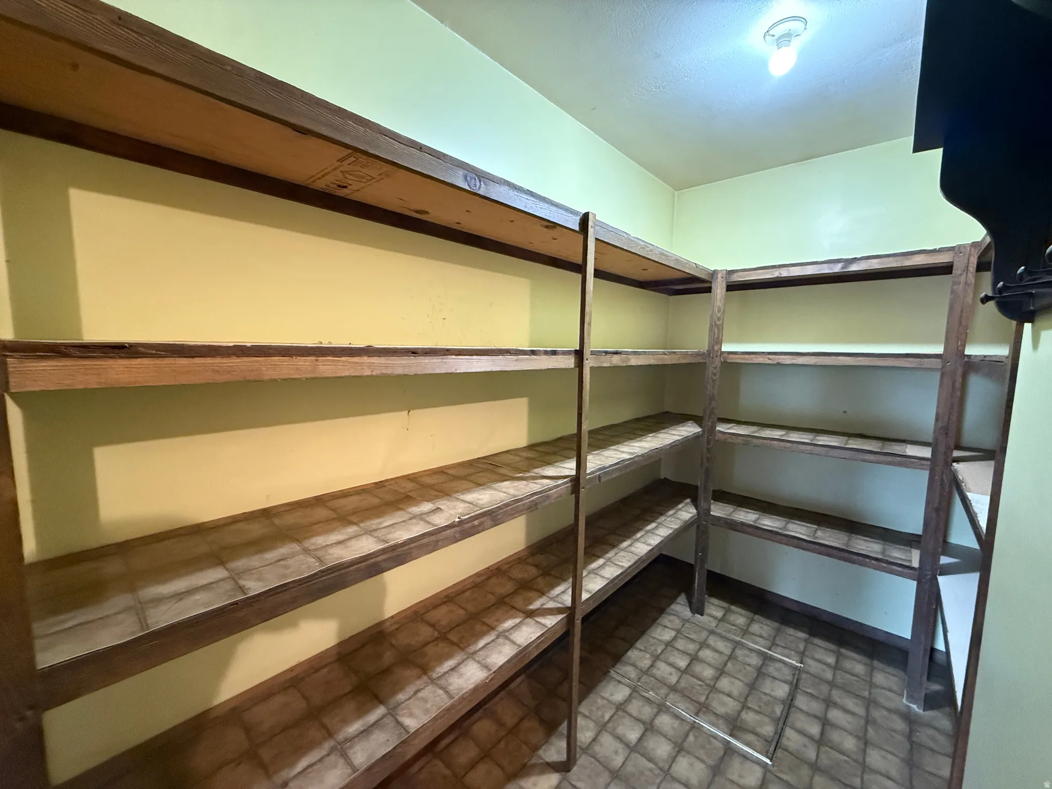 Spacious utility room featuring extensive built-in shelving, durable tile flooring, and a ceiling-mounted light fixture
