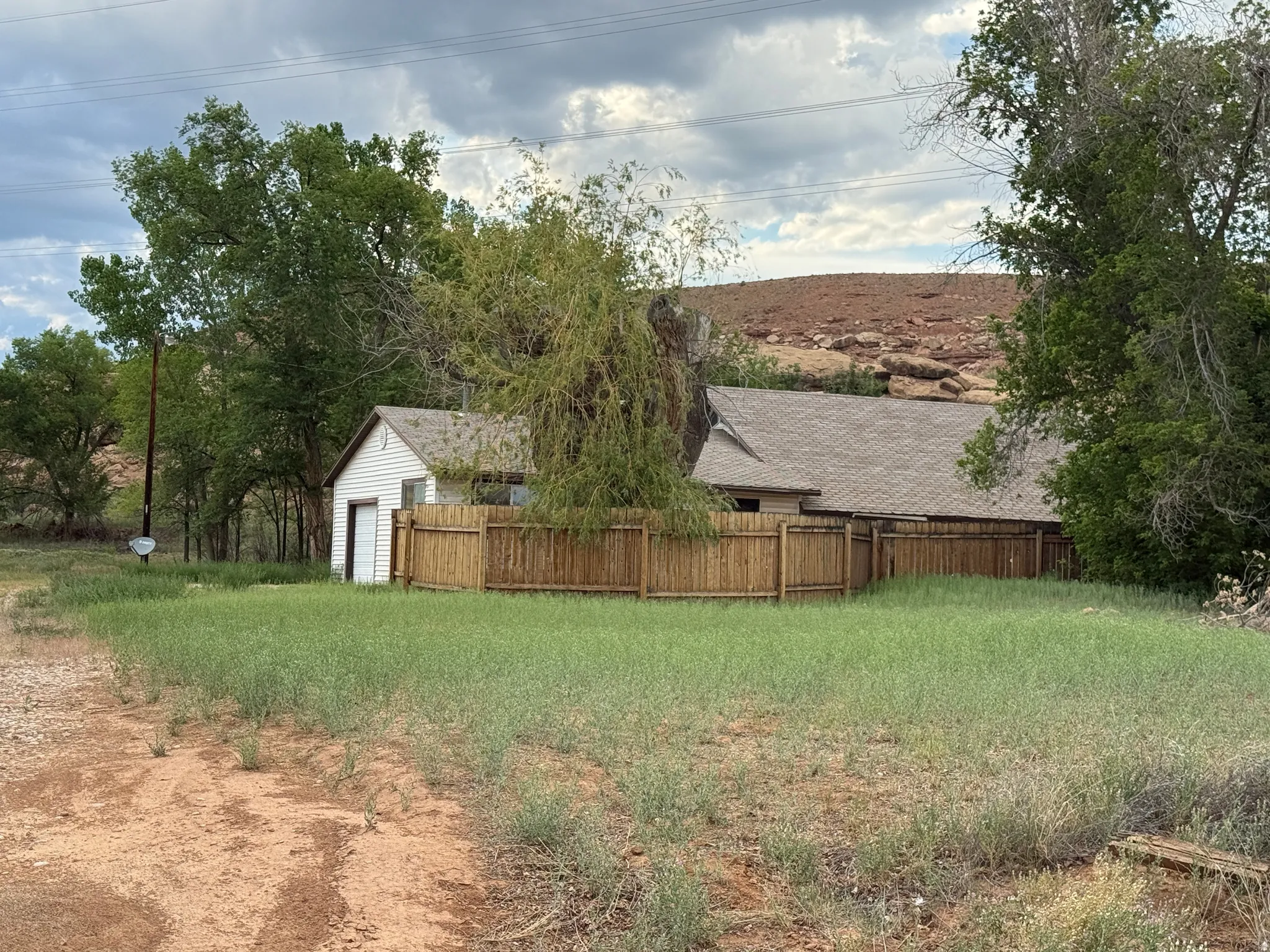 Single-story residence featuring a shingled roof, attached garage with a roll-up door, and a wooden privacy fence