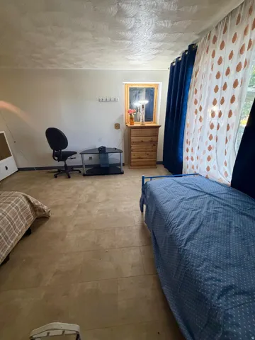 Room with light-toned rectangular floor tiles, textured ceiling, and a framed window