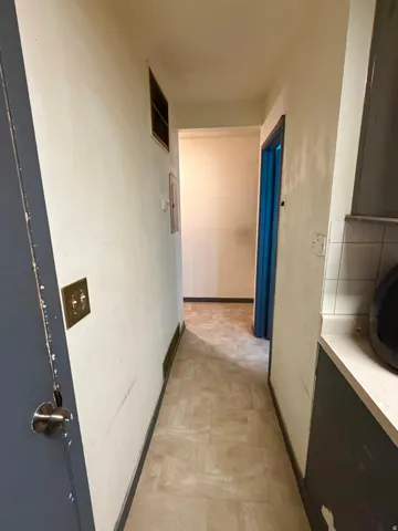 Hallway featuring light-toned tile flooring, light-colored walls, and a dark blue door frame