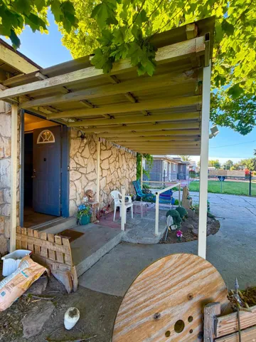 Stone veneer exterior entrance featuring a covered patio structure and a blue entry door with an arched window insert