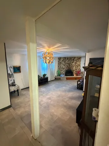 Spacious living area featuring stone-clad fireplace, tile flooring, and a decorative orb chandelier