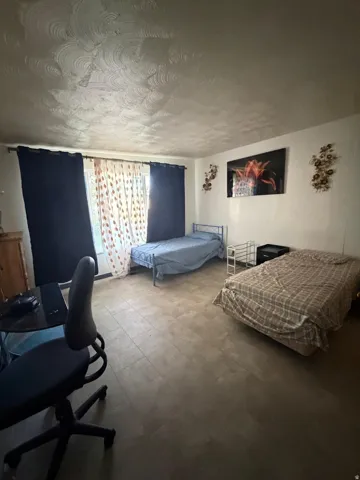 Spacious room featuring wood-finish flooring, a textured ceiling, and a large window