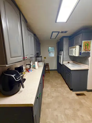 Galley kitchen featuring light-toned countertops and a tile backsplash