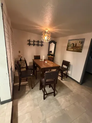 Dining area featuring a contemporary overhead light fixture, light-toned tile flooring, and a dark wood-finish table