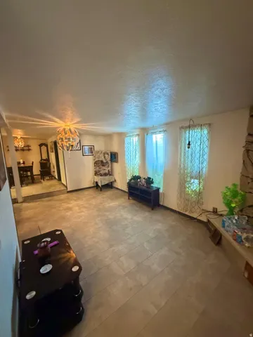 Spacious room featuring tile flooring, three windows with vertical blinds, and a stone-clad fireplace