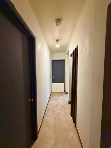 Elongated hallway with light-toned tile flooring